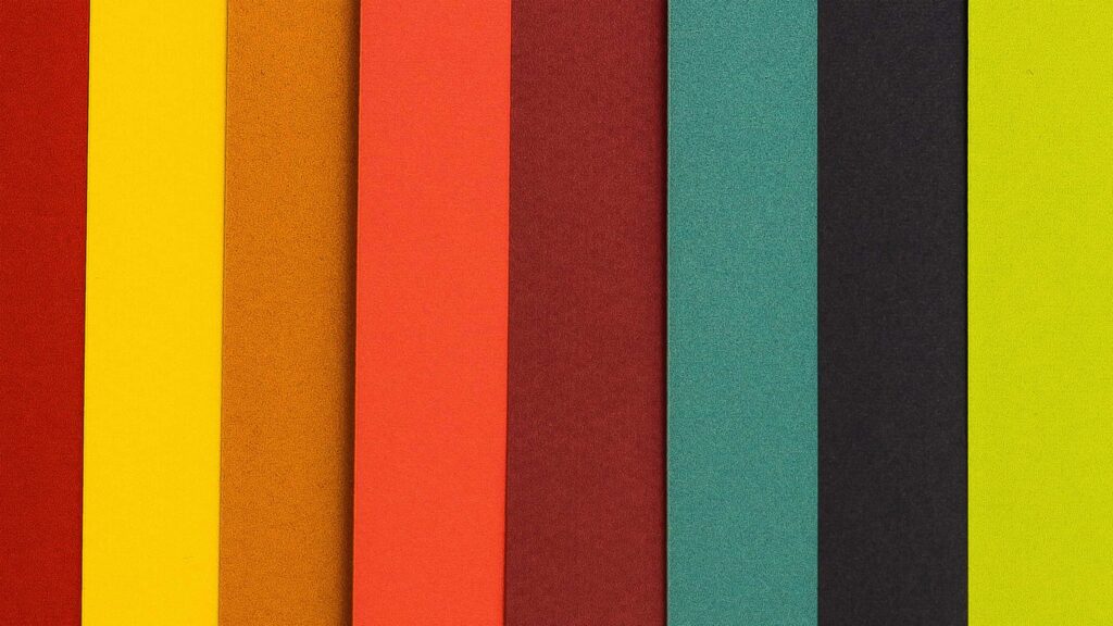 Papel de colores cortados en linea verticales y sobre puestas, rojo, amarillo, ocre, naranja, marrón, verde, negro y verde limón